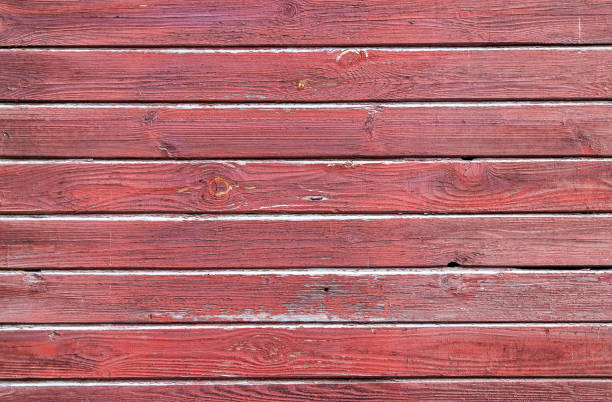 Photo of Texture of a wall made of old wooden panels covered with peeled red paint as a background