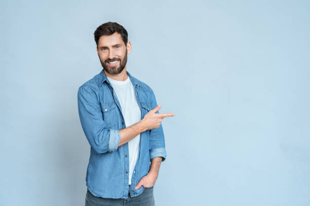 istock Smiling man freelancer pointing right with index finger and looking at camera 1347960526