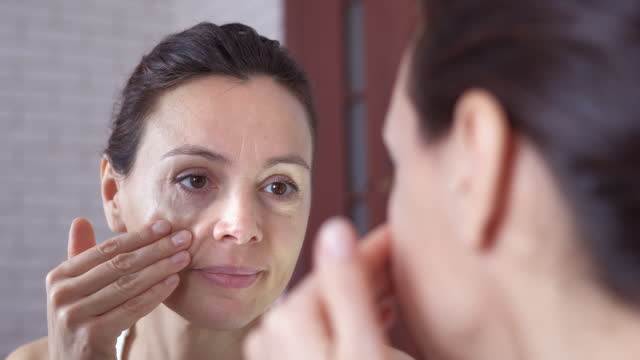 Woman touching face in the mirror.