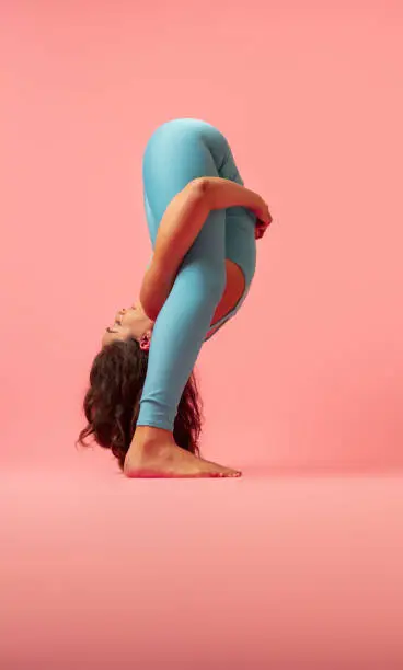 One woman doing yoga on a pink background.