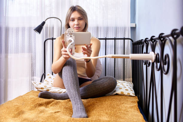 istock Smartphone is fixed by phone holder to bed by woman. 1347968841