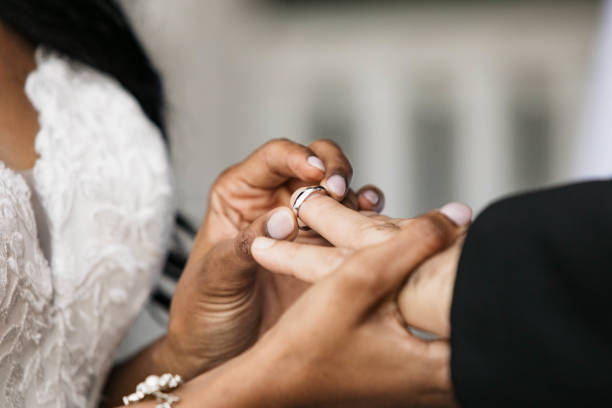 istock Bride putting on wedding ring on Groom's finger 1347968846
