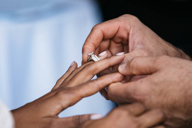 istock Groom putting on wedding ring on bride finger 1347968847
