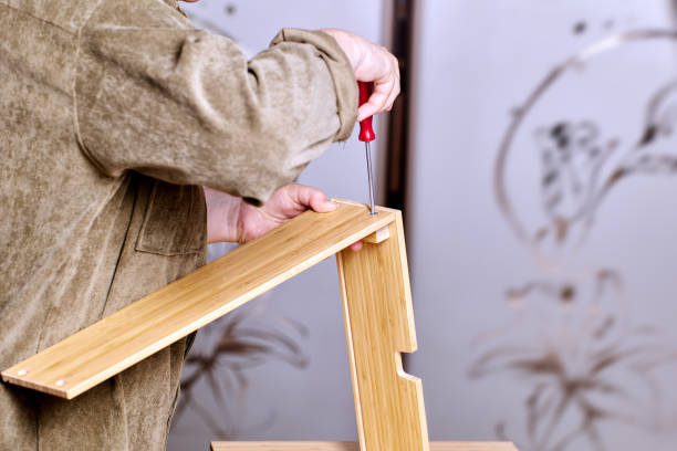 istock Handyman is assembling flat pack furniture using screws and screwdriver. 1347968866