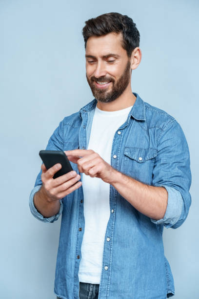 istock Handsome guy perfect appearance browsing telephone against blue copy space 1347969041