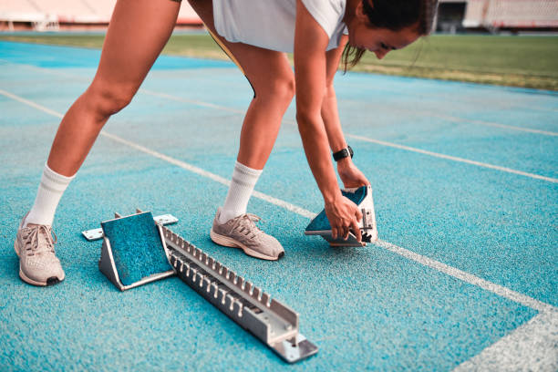 istock Athletic Female Setting Up Spring Starting Blocks On Running Track 1347971904
