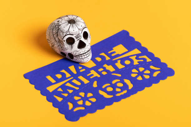 Day of the dead pottery skull (calavera) on blue papel picado on yellow background, Dia de Muertos background Day of the dead pottery skull (calavera) on blue papel picado on yellow background, Dia de Muertos background day of the dead photos stock pictures, royalty-free photos & images