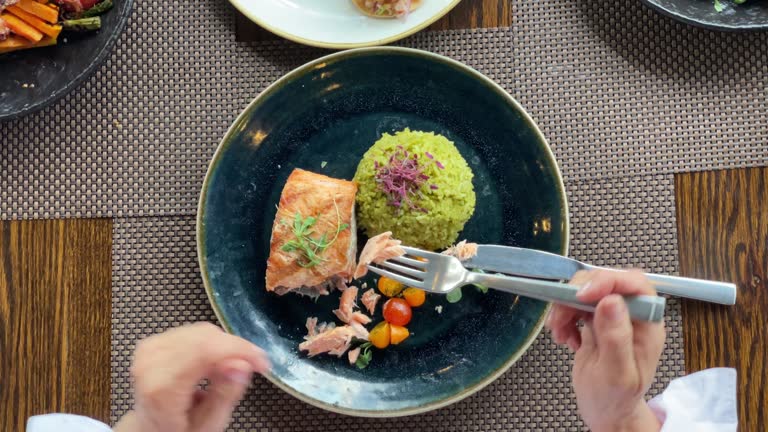 Unrecognizable woman enjoying a delicious healthy meal with salmon, rice and vegetables - High angle view
