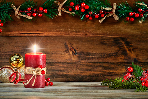 Christmas concepts: Red candle with Christmas decoration on rustic background with copy space.