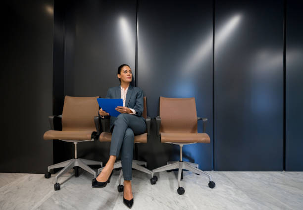 mujer de negocios esperando afuera de una oficina para una entrevista de trabajo - unemployment waiting in line waiting room interview fotografías e imágenes de stock