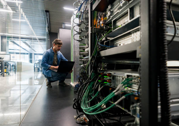 técnico informático arreglando un servidor de red en la oficina - cable de ordenador fotografías e imágenes de stock