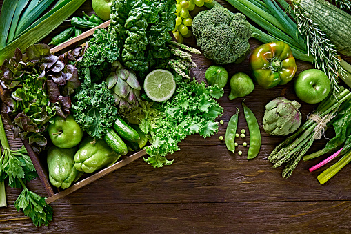 Table top view background of a variation green vegetables for detox and alkaline diet. Set in a crate on a wooden rustic table
