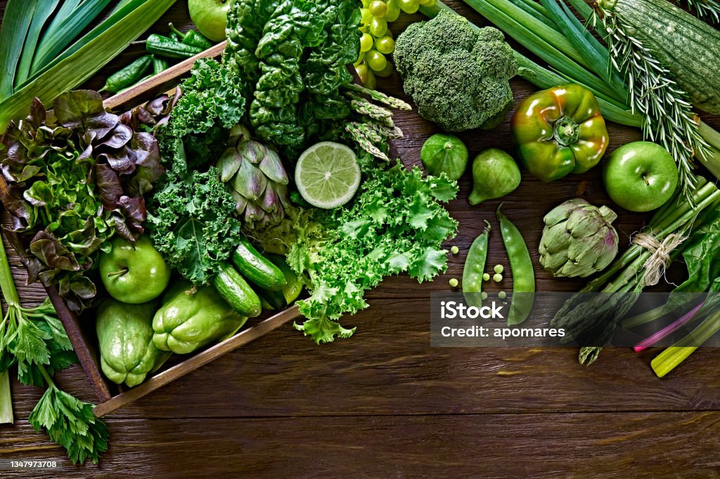 Table top view background of a variation green vegetables for detox and alkaline diet. Set in a crate on a wooden rustic table Alkaline Stock Photo
