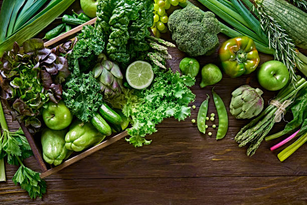 Table top view background of a variation green vegetables for detox and alkaline diet. Set in a crate on a wooden rustic table stock photo