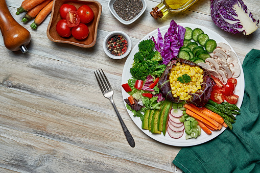 Healthy eating and diet concepts. Colorful spring salad on rustic white wood table. Included ingredients: Chicken, tomatoes, broccoli, lettuce, bell peppers, mushroom, carrots, radicchio, almonds.