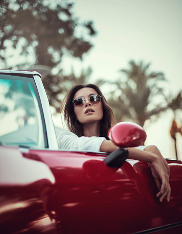 Young woman enjoying the outdoors in a convertible classic car.