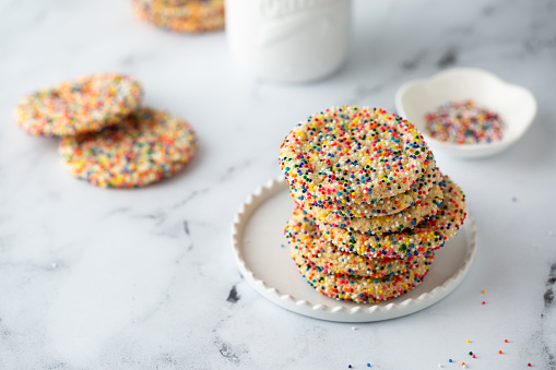 Sugar cookies with sprinkles and a bottle of milk on white background