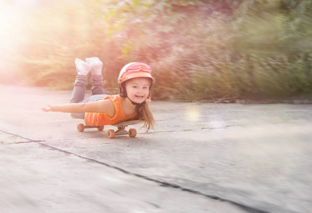 Happy child lies on a skateboard and rides cheerfully along the road ahead