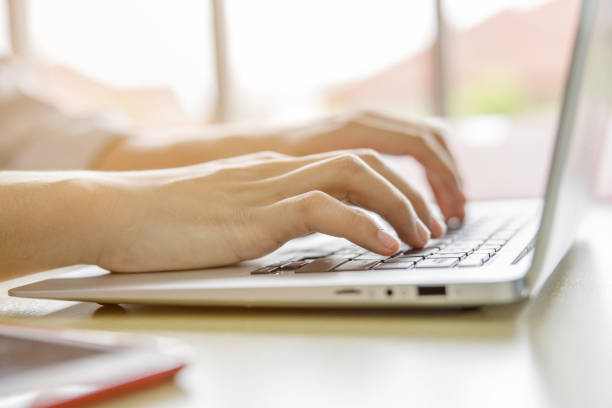istock close up hands typing on laptop keyboard and windows light background 1347988275