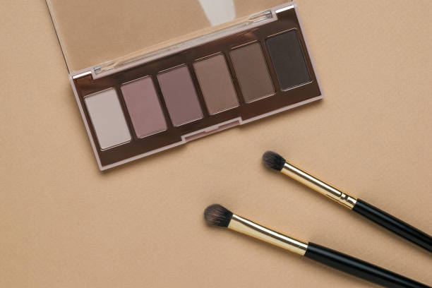 istock Makeup brushes and an open box with a set of eye shadow on a beige background. 1347992568