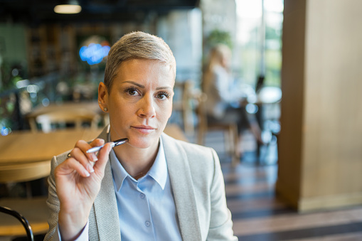 Portrait of businesswoman contemplating while working in coffee shop and looking at camera.