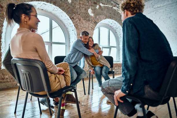 istock Relieved man and woman hugging giving psychological support empathy during a group therapy session, friends people embracing comforting helping overcome problems addiction at psychotherapy counseling. 1347995018