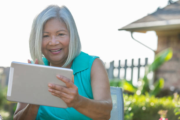 istock Senior Woman using digital tablet to video chat with family 1347996016