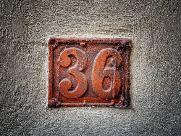 istock Old rusty metal plate with number 36 hung on a brick wall 1347997559