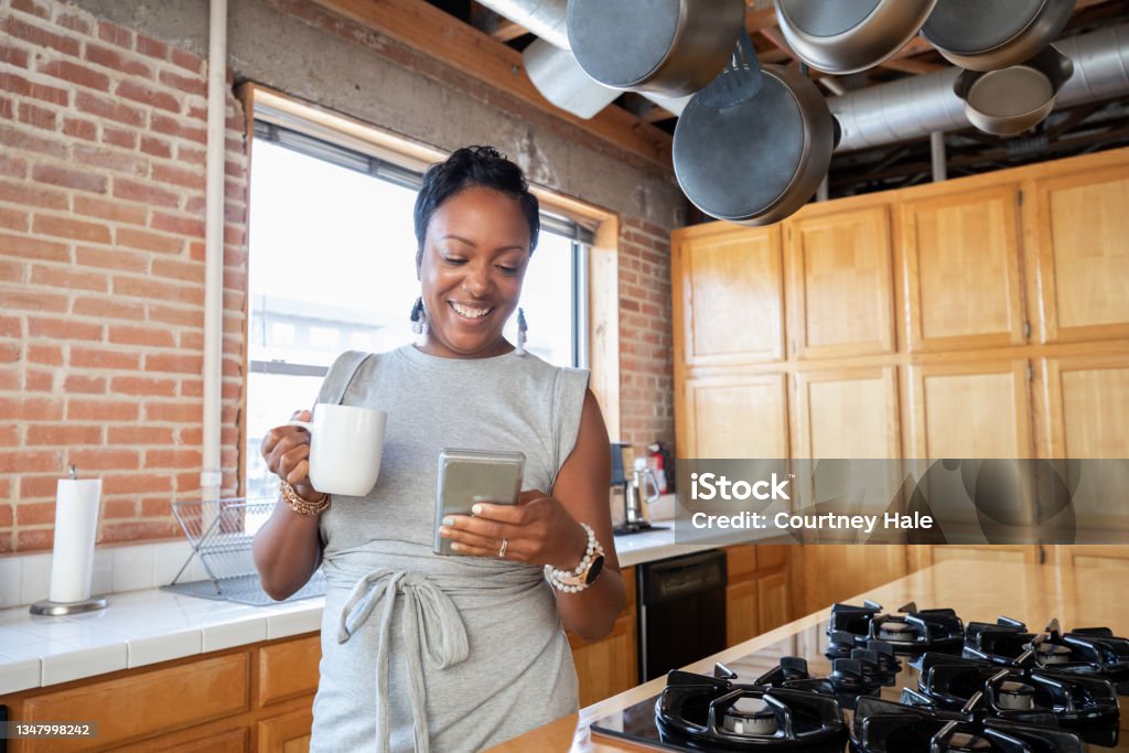 Adult Woman holding cup of coffee while texting on smartphone One Woman Only Stock Photo