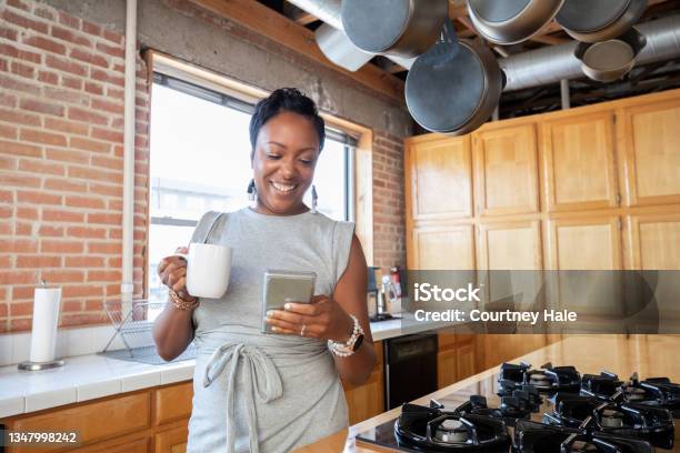Adult Woman Holding Cup Of Coffee While Texting On Smartphone Stock Photo - Download Image Now