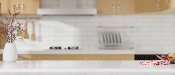 istock Kitchen island countertop on blurred modern white and wooden kitchen interior. 1348000324