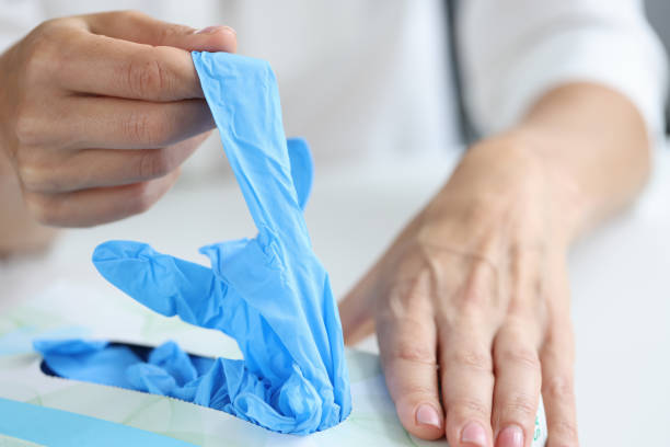 mujer saca guantes desechables del primer plano de la caja - guante quirúrgico fotografías e imágenes de stock
