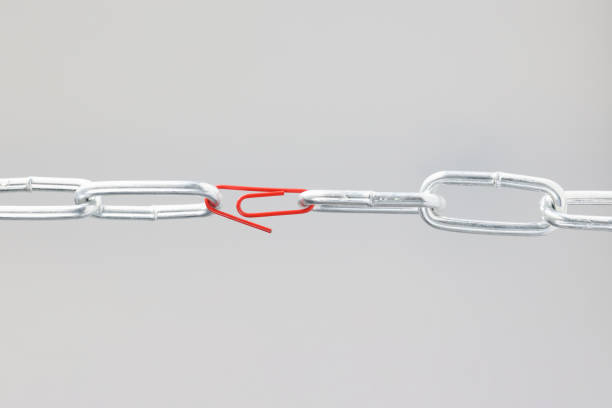 Chrome chain in middle with red paper clip. Broken chain linked by paper clip concept