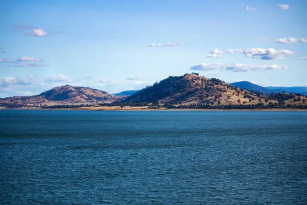 Photo of Blue waters of the Hume Dam across Murray River, New South Wales, Australia with sun shining upon hills in background