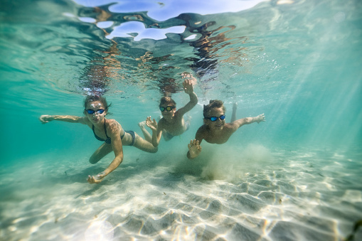 Three teenagers swimming underwater in the sea. The kids are enjoying the summer vacations.
Canon R5