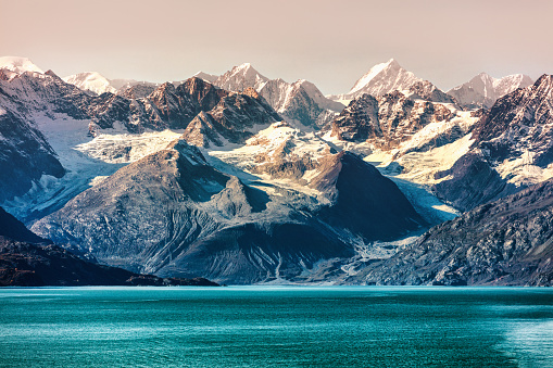 Parque Nacional Glacier Bay, Alaska, Estados Unidos. Vista del viaje en crucero por Alaska de las montañas cubiertas de nieve al atardecer. Increíble vista del paisaje glaciar desde las vacaciones en crucero que muestran picos nevados de las montañas. photo