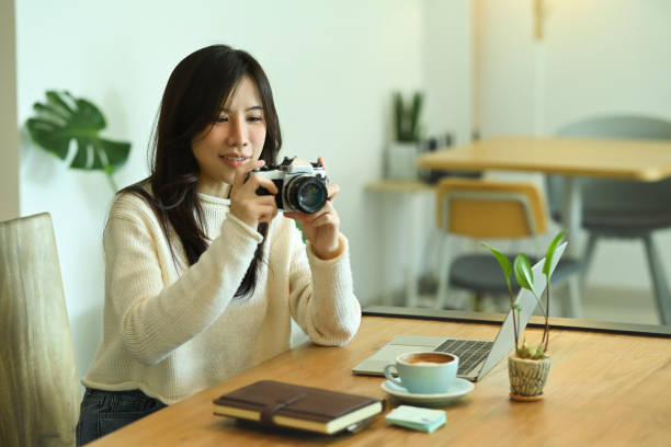 istock Smiling young woman holding camera and checking picture previews. 1348012331