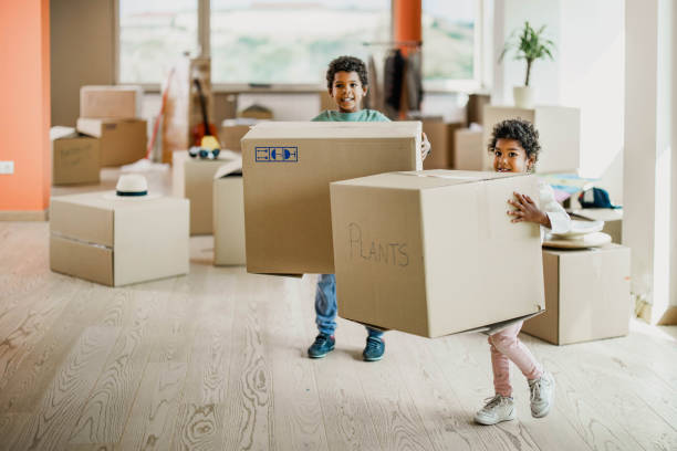 istock Small black kids carrying cardboard boxes in their new home. 1348015349