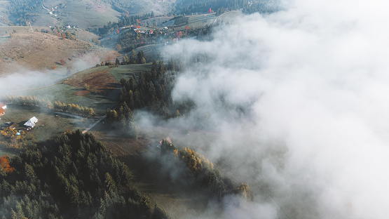 Aerial view of landscape pictures of small country houses on top of a hill in autumn in foggy mountains at sunrise