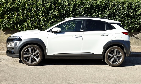 Udine, Italy.October 15, 2021. Hyundai Kona X parked at the roadside. Side view with a hedge on background.