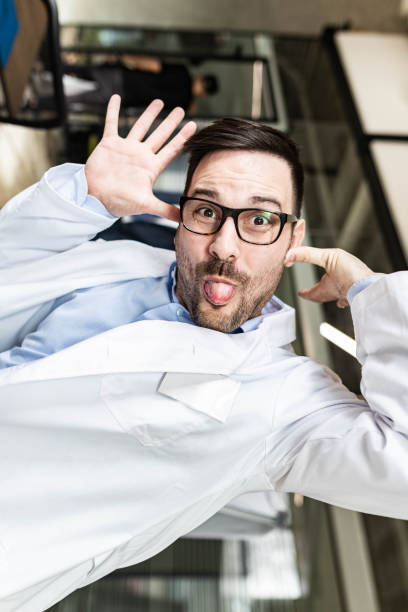 Young doctor having fun while making a face in his office and looking at camera.