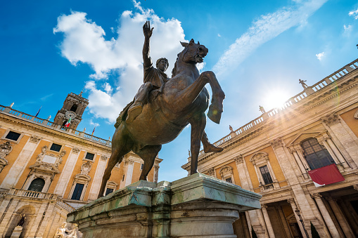 An intense blu sky above the majestic equestrian statue of Emperor Marcus Aurelius, located in the center of Piazza del Campidoglio (the Roman Capitol Square) on the Capitoline Hill, square designed by Michelangelo in 1534 in the historic heart of Rome. In the background, the ancient Palazzo Senatorio, seat of the municipal government of the Eternal City. The original statue of Marcus Aurelius is kept inside the Capitoline Museums. In 1980 the historic center of Rome was declared a World Heritage Site by Unesco. Super wide angle and high definition image.