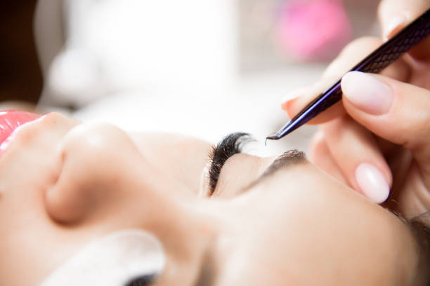 istock Beautiful young woman during eyelash extension, Close up. 1348019220