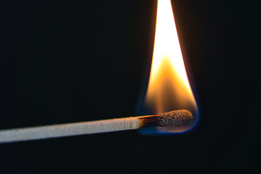A selective focus of a match on fire on black background