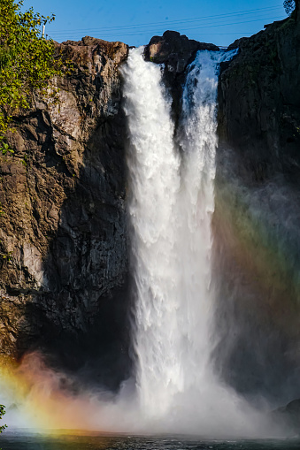 A huge waterfall near Seattle area with sunshine falling on the water drops and forming a beutiful rainbow.