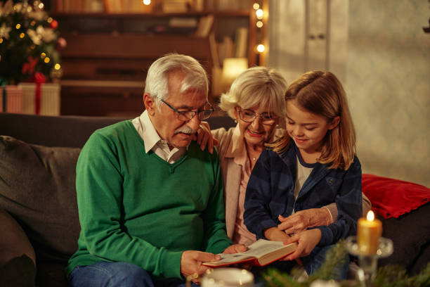 istock Grandparents sitting with their grandson at home and reading a book 1348024378