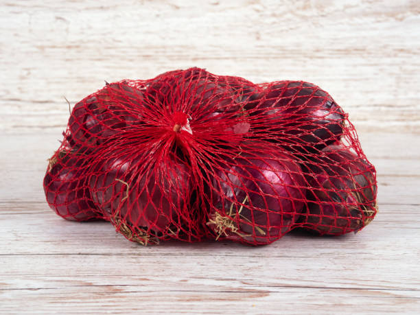 istock A small bag with red onions on a light wooden background 1348025128