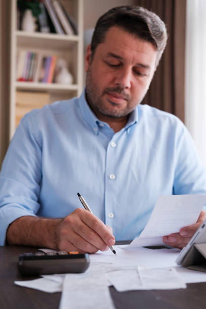 istock Man calculating personal expenses at home 1348027500