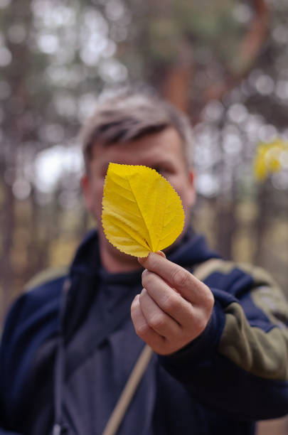 istock Leafy season. A man holds a yellow fallen tree leaf in his outst 1348027913