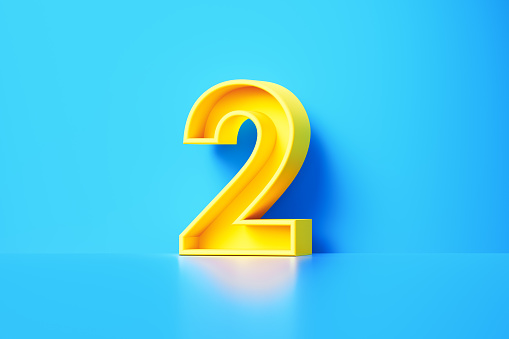 Yellow number two sitting on blue background. Horizontal composition with copy space.